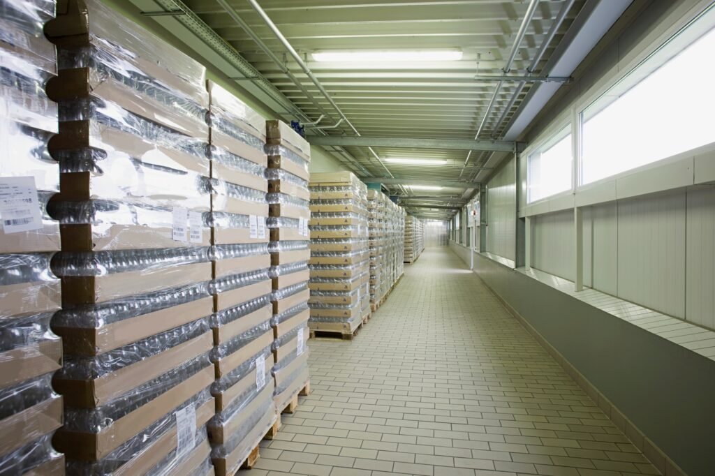 A long corridor in a warehouse stacked with pallets of goods