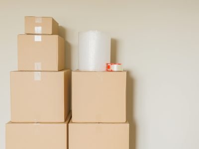 Variety of Packed Moving Boxes with Materials In Empty Room Against Wall.